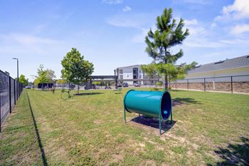 A green cylindrical object is placed on a grassy field.